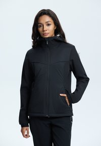 Veste isolante noire avec fermeture éclair, col haut, poches latérales et poignets élastiques. Elle présente un design épuré et minimaliste avec une texture lisse.