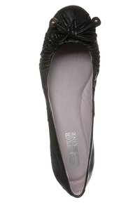 Svart läderballetskor med en samlad topp, matchande rosett och guldkant. Insidan har en ljusgrå innersula med varumärkeslogotyp.