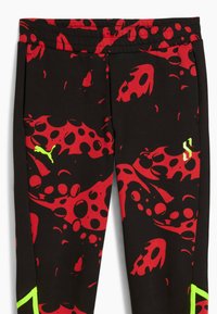 Black pants with a bold red and black splatter pattern, featuring a yellow Puma logo on the side and a stylized letter on the other.