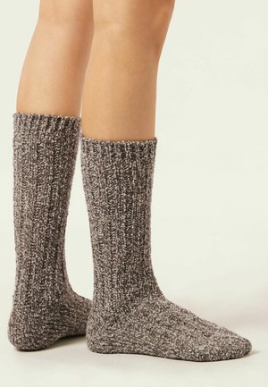 Chaussettes en tricot à chevilles avec un motif en côtes, présentant une texture marbrée gris et blanc. Ajustement flexible s'étendant jusqu'à mi-mollet.