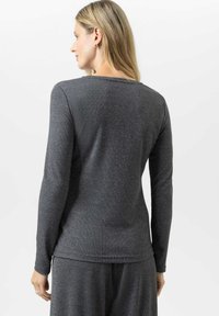 Langärmliges Oberteil aus dunkelgrauem Stoff mit subtiler Textur, runder Halsauschnitt und taillierter Silhouette, von hinten gezeigt.