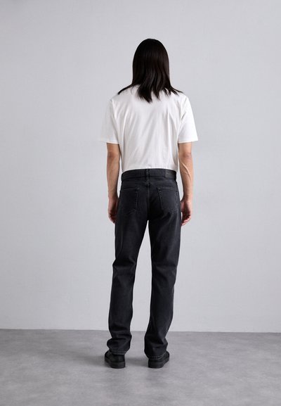 Black denim jeans with a straight cut, paired with a plain white t-shirt; features a belt and two back pockets.