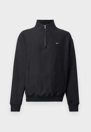 Felpa nera con colletto alto e zip, maniche lunghe, tasche laterali e vita elastica. Presenta un piccolo logo Nike bianco sul petto.