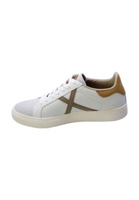 Basket blanche avec matériau perforé, accents marron et design à lacets. La pointe arrondie et la semelle en caoutchouc améliorent le confort et la stabilité.