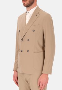 Beige dubbele breasted blazer met een gekleurde revers, vier knopen, twee voorzakken en een gladde stofstructuur.