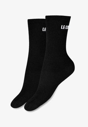 Calcetines de algodón negros de corte crew con textura acanalada, que presentan el texto blanco "LE CO" en la parte superior. Acabado suave y forma estándar de calcetín.