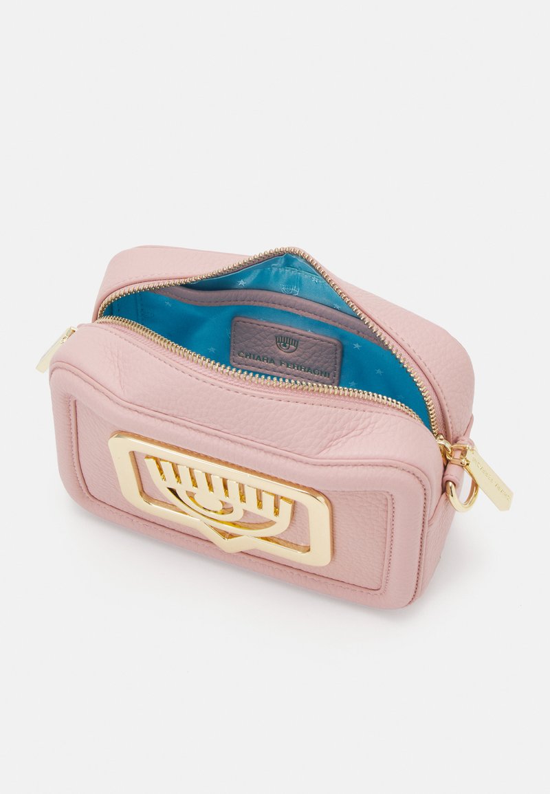 Borsa in pelle rosa con accessori in hardware dorato e chiusura con zip. L'interno presenta una fodera blu e una piccola etichetta grigia con logo in rilievo.