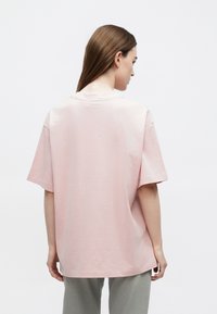 Απαλό ροζ φαρδύ t-shirt κατασκευασμένο από μαλακό βαμβάκι, με απλή στρογγυλή λαιμόκοψη και κοντά μανίκια σε χαλαρή εφαρ�μογή.