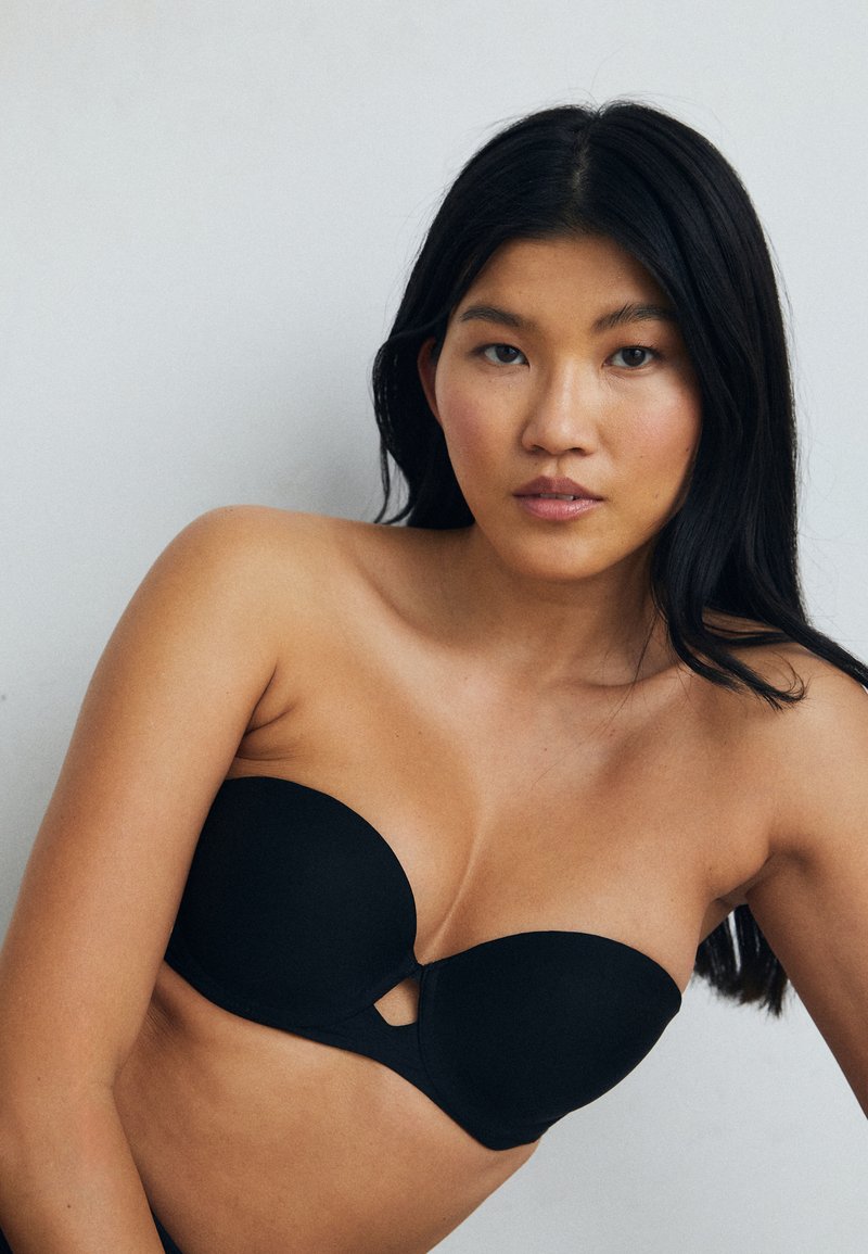 Zwarte strapless beha van gladde stof met zachte cups en een centrale uitsnijding. Naadloos ontwerp voor meer veelzijdigheid en comfort.