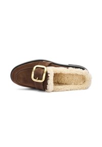 Mocassin en suède brun avec un intérieur en shearling beige moelleux, un accent en boucle dorée et une semelle en caoutchouc noir. Texture lisse et design à enfiler.