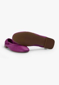 Mocasines tejidos púrpuras con un tacón bajo, con una parte superior texturizada y una suela marrón lisa, que muestran un diseño elegante.