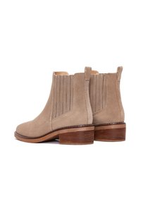 Stivaletti in suede beige alla caviglia con inserti laterali elastici, tacco in legno basso e impilato, punta rotonda e dettagli di cucitura sui lati.