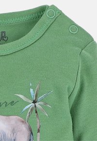 Groene katoen rompertje met een ronde halslijn en twee drukknoopjes. Het ontwerp bevat een graphic van een dier met palmbladeren.