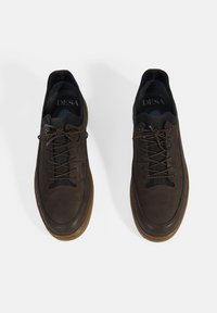 Baskets en cuir brun avec une texture lisse, bout rond et semelle en caoutchouc brun contrastée. Comprend des lacets et un branding minimal à l'intérieur.