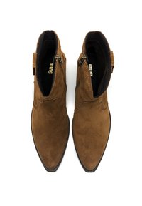 Par de botas de tobillo de ante marrón con puntas afiladas, cremalleras laterales y costuras decorativas, mostradas desde arriba sobre un fondo blanco.