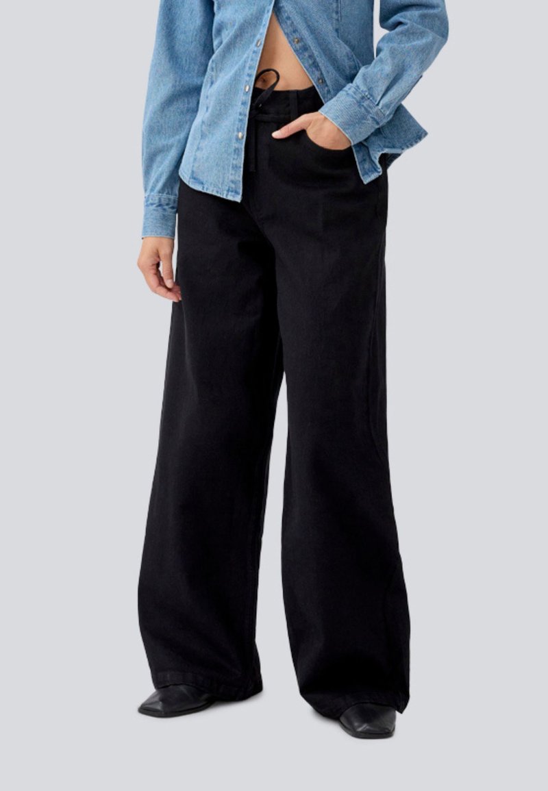 Svart vid ben bukse laget av denim. Høyt liv med en løs passform, med sidelommer og en jevn, matt tekstur.