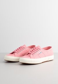 Rosa.Canvas sneakers med vit gummisula, rund tå och snörningsdesign. Funktioner inkluderar textilmaterial och varumärkeslogotyp på sidan.