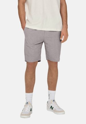 Sivé, textúrované šortky s elastickým pásom, bočnými vreckami a voľným strihom. Kombinované s bielymi teniskami a rebrovanými bielymi ponožkami.