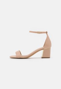 Beige heeled sandals with an ankle strap, smooth material, wide toe band, and square block heel accented with gold detailing.