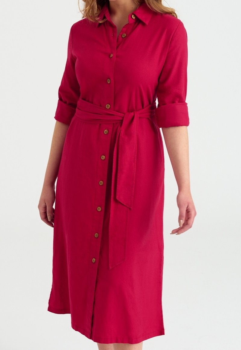 Femme portant une robe midi rouge à boutons, manches retroussées et ceinture assortie nouée à la taille.