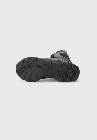 Semelle de botte de randonnée noire avec un motif de semelle texturé, des rainures profondes pour une meilleure traction, et un matériau en caoutchouc robuste et durable.