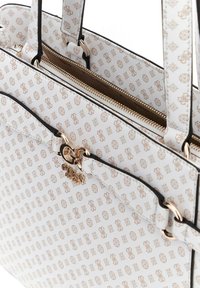 Borsa a tracolla bianca con motivo geometrico dorato, hardware dorato, chiusura zip e dettagli neri. Presenta doppi manici e una forma strutturata.