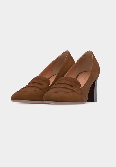 Chaussures pour femmes à talons hauts en daim marron, avec des bouts pointus et des coutures de style mocassin sur fond blanc.
