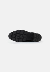 Suela de zapato negra con un diseño texturizado y resistente, con surcos profundos para agarre. Fabricada con material de goma duradero.