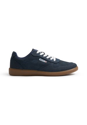 Zapatillas de lona navy con cordones blancos, suela de goma y textura sutil; presenta una etiqueta de logo en el lado y un diseño redondeado.
