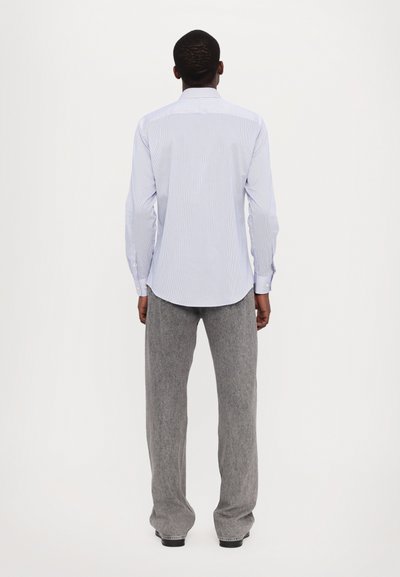 Camicia a maniche lunghe a righe in blu chiaro e bianco, in tessuto di cotone, con polsini abbottonati e orlo curvo, abbinata a pantaloni larghi grigi in tessuto testurizzato.