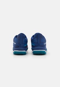 Pantofi sport albaștri cu partea superioară texturată din plasă, accente contrastante de teal și talpă intermediară albă. Dispune de o talpă din cauciuc cu rulouri pentru aderență.