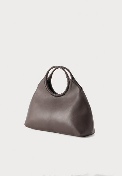 Σκούρα καφέ δερμάτινη τσάντα χειρός με στρογγυλεμένες πλεκτές λαβές και χαλαρή, τριγωνική μορφή πάνω σε ανοιχτό φόντο.