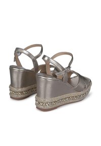 Sandali con tacco a cuneo in argento metallico con cinturini alla caviglia, caratterizzati da una rifinitura dorata texturizzata e perline decorative attorno alla base.