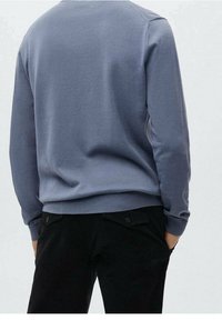 Sweat-shirt gris foncé avec un col rond, manches longues et poignets côtelés, fabriqué à partir d'un tissu en mélange de coton lisse, porté avec un pantalon noir.