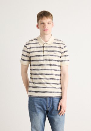 Gestreiftes Poloshirt in Creme mit marineblauen und hellgrauen horizontalen Linien, kurzen Ärmeln und Knopfkragen. Kombination mit blauen Jeans.