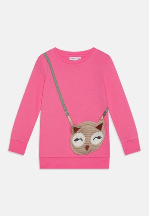 Chemise rose à manches longues avec un motif imprimé d'une lanière verte et un sac à main en forme de visage de chouette au crochet sur le devant.
