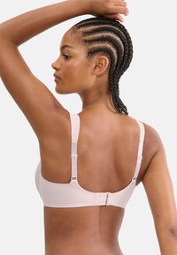 Ανοιχτό ροζ σουτιέν με ρυθμιζόμενους ιμάντες, υφασμάτινη υφή και κούμπωμα με άγκιστρο στο πίσω μέρος, παρουσιάζοντας ένα ομαλό, περιγραμμικό σχήμα.