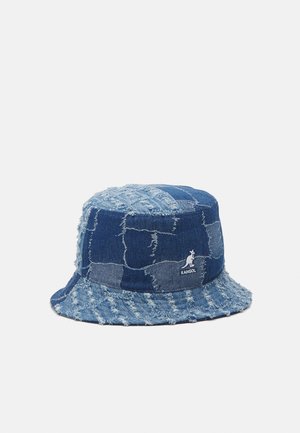 Cappello a secchiello in denim con un design patchwork, caratterizzato da diverse tonalità di blu e bordi sfilacciati. Include il logo Kangol sul lato.