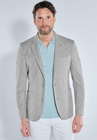 Gray textured blazer with two front pockets, single button closure, and peaked lapels, layered over a light blue polo shirt.