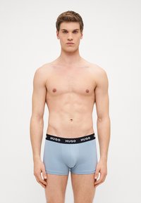 Világoskék pamut boxer alsónadrág fekete elasztikus derékkal, rajta a "HUGO" felirat fehér színben. Testhez simuló fazon.