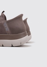 Braune Wildleder-Slipper mit strukturiertem Finish, ausgestattet mit einer hellgrauen Sohle und einer Zugschlaufe an der Ferse für einfaches An- und Ausziehen.