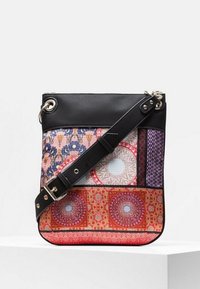 Black crossbody bag with adjustable strap, featuring colorful patchwork patterns in red, purple, pink, and blue with floral and geometric designs.