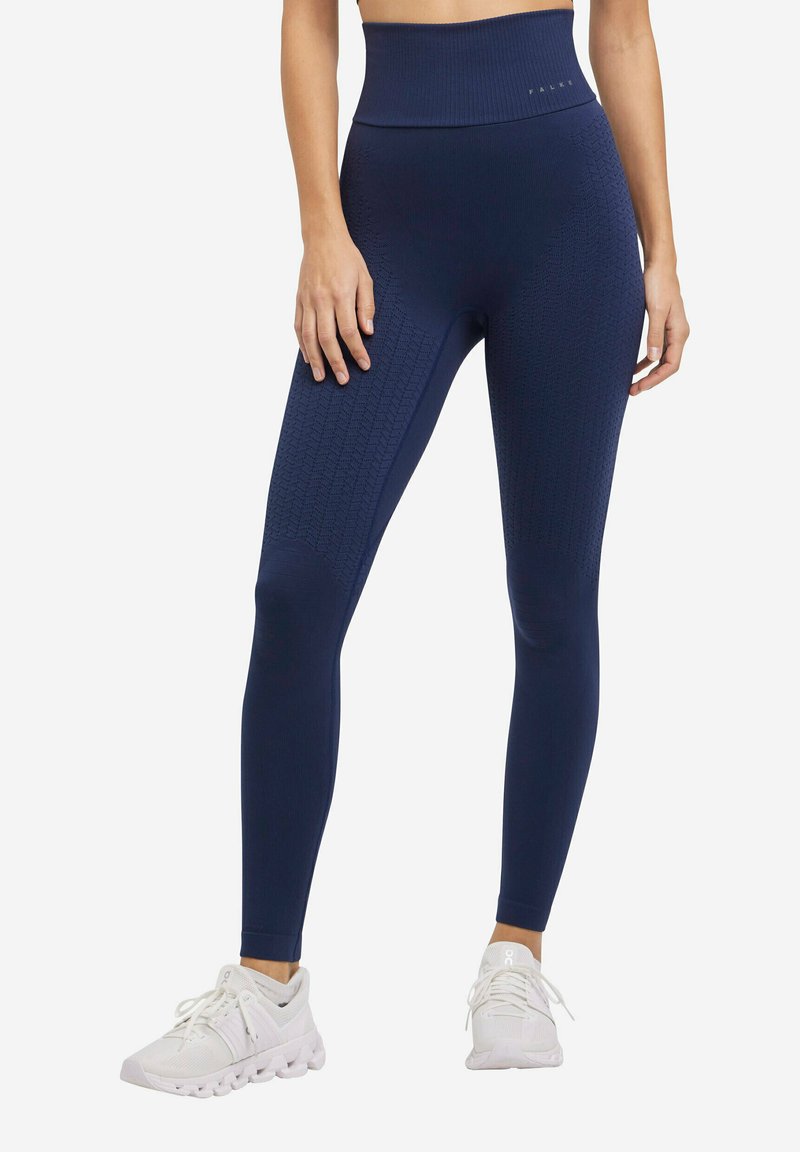 Hoge taille navy leggings van gemêleerd stof met een geribbeld patroon. Gecombineerd met witte sportschoenen. Heeft een naadloze constructie.