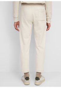Crème-kleurige joggers met een taps toelopende pasvorm, een elastische tailleband en een achterzak. Gemaakt van zachte stof, met geribde manchetten.