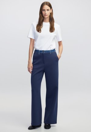 Marine brede-broek met een elastische tailleband in denimmateriaal. In combinatie met een effen witte T-shirt met korte mouwen. Glad stof en een relaxte pasvorm.