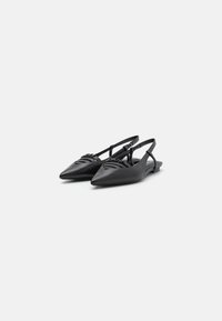 Sapatos pretos de biqueira pontiaguda e tacão aberto, com um acabamento em couro liso, apresentando alças estruturadas e um detalhe de trama na parte superior.