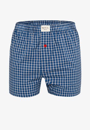 Męskie bokserki w niebiesko-biało-czarną kratę z elastycznym pasem, czerwonym guzikiem przy kroku oraz białą metką "Phil & Co. Berlin".