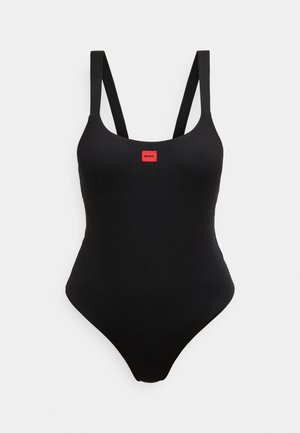 Costume intero nero a coste con spalline regolabili e un piccolo dettaglio con logo rosso al centro frontale. Texture liscia e forma aderente.