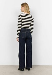 Maglietta a maniche lunghe a righe nere e crema abbinata a jeans a gamba larga in denim blu scuro a vita alta, con classiche tasche posteriori.