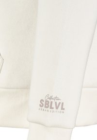 Weißes Baumwoll-Sweatshirt mit gerippten Bündchen und Saum. Akzentuiert mit dem Logo "Collection SBLVL Urban Edition" in Hellgrau auf dem Ärmel.